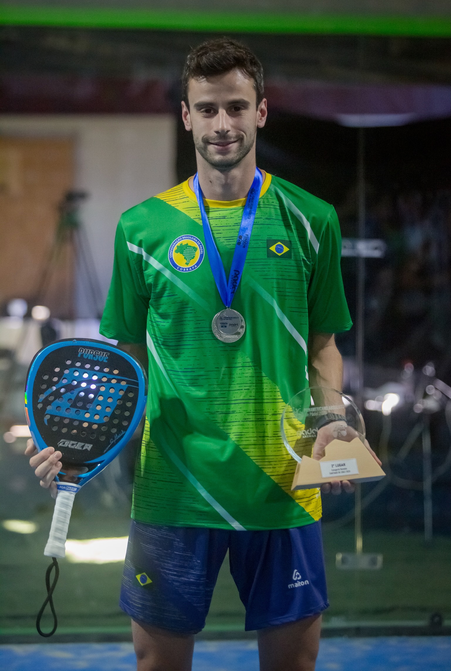 Gabriel Almeida com o uniforme da Seleção Brasileira, medalha no pescoço e troféu na mão